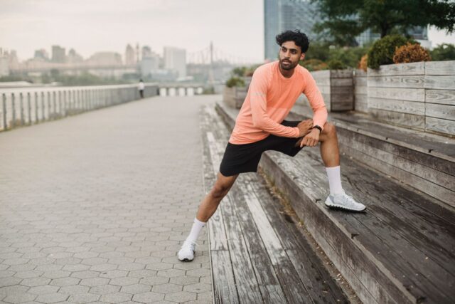 Copii care joacă fotbal pe un teren cu iarbă, alergând după minge sub privirile antrenorului